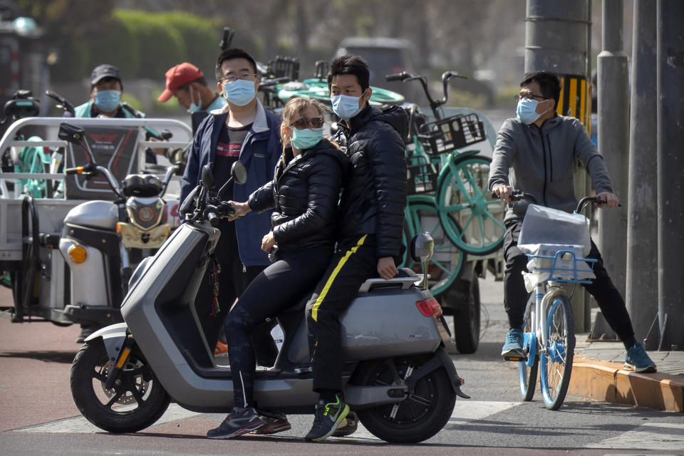 People pause at an intersection during a national moment of mourning for victims of the coronavirus, in Beijing on Saturday, April 4, 2020. With air raid sirens wailing and flags at half-staff, China on Saturday held a three-minute nationwide moment of reflection to honor those who have died in the coronavirus outbreak, especially "martyrs" who fell while fighting what has become a global pandemic. (AP Photo/Mark Schiefelbein)