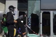 Pro-democracy protesters walk by a vandalized Starbucks cafe on the campus of the Hong Kong Polytechnic University, in Hong Kong, Wednesday, Nov. 13, 2019. Police have increased security around Hong Kong and its university campuses as they brace for more violence after sharp clashes overnight with anti-government protesters. (AP Photo/Vincent Yu)