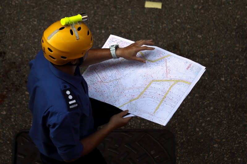 A fire services department officer holds a map of the sewage system as they prepare to search anti-government protesters who escaped from the Hong Kong Polytechnic University (PolyU) after being barricaded by police officers in Hong Kong