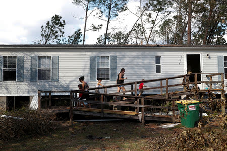 Roommates Lee Schaffrick (R) and Joy Aguilar enter their home with their respective children amid debris from hurricane Michael in Fountain, Florida, U.S., October 15, 2018. REUTERS/Terray Sylvester