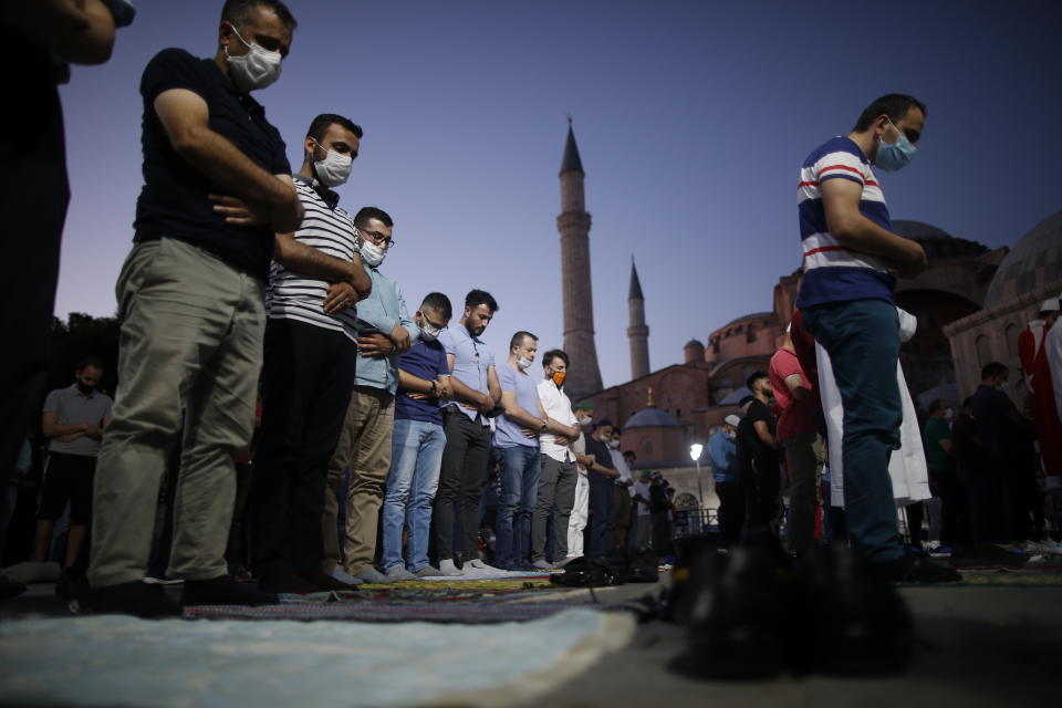 Muslims offer their evening prayers outside the Byzantine-era Hagia Sophia, one of Istanbul's main tourist attractions in the historic Sultanahmet district of Istanbul, following Turkey's Council of State's decision, Friday, July 10, 2020. Turkey's highest administrative court issued a ruling Friday that paves the way for the government to convert Hagia Sophia - a former cathedral-turned-mosque that now serves as a museum - back into a Muslim house of worship. The Council of State threw its weight behind a petition brought by a religious group and annulled a 1934 cabinet decision that changed the 6th century building into a museum. (AP Photo/Emrah Gurel)