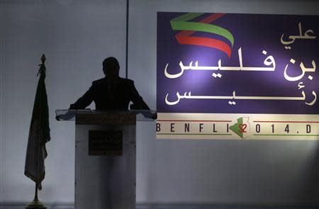 Former Prime Minister Ali Benflis is silhouetted against a banner featuring his name and word 'president' during a news conference to announce his candidacy for the presidential election in Algiers January 19, 2014. REUTERS/Louafi Larbi