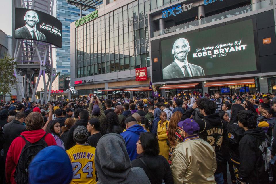 People gather around a makeshift memorial for former NBA and Los Angeles Lakers player Kobe Bryant after learning of his death, at LA Live plaza in front of Staples Center in Los Angeles on January 26, 2020. - Nine people were killed in the helicopter crash which claimed the life of NBA star Kobe Bryant and his 13 year old daughter, Los Angeles officials confirmed on Sunday. Los Angeles County Sheriff Alex Villanueva said eight passengers and the pilot of the aircraft died in the accident. The helicopter crashed in foggy weather in the Los Angeles suburb of Calabasas. Authorities said firefighters received a call shortly at 9:47 am about the crash, which caused a brush fire on a hillside. (Photo by Apu GOMES / AFP) (Photo by APU GOMES/AFP via Getty Images)