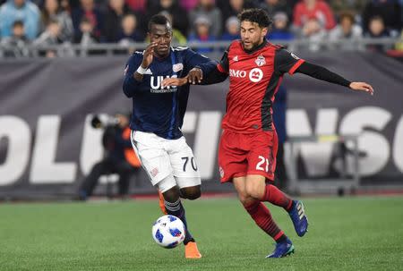 May 12, 2018; Foxborough, MA, USA; New England Revolution forward Cristian Penilla (70) and Toronto FC midfielder Jonathan Osorio (21) battle for the ball during the first half at Gillette Stadium. Mandatory Credit: Bob DeChiara-USA TODAY Sports