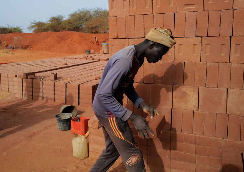 A worker carries a newly made brick at the Elementerre factory in Mbour