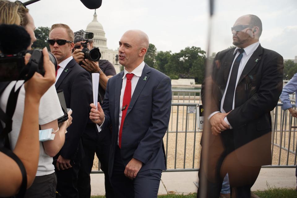 Three men stand wearing suits