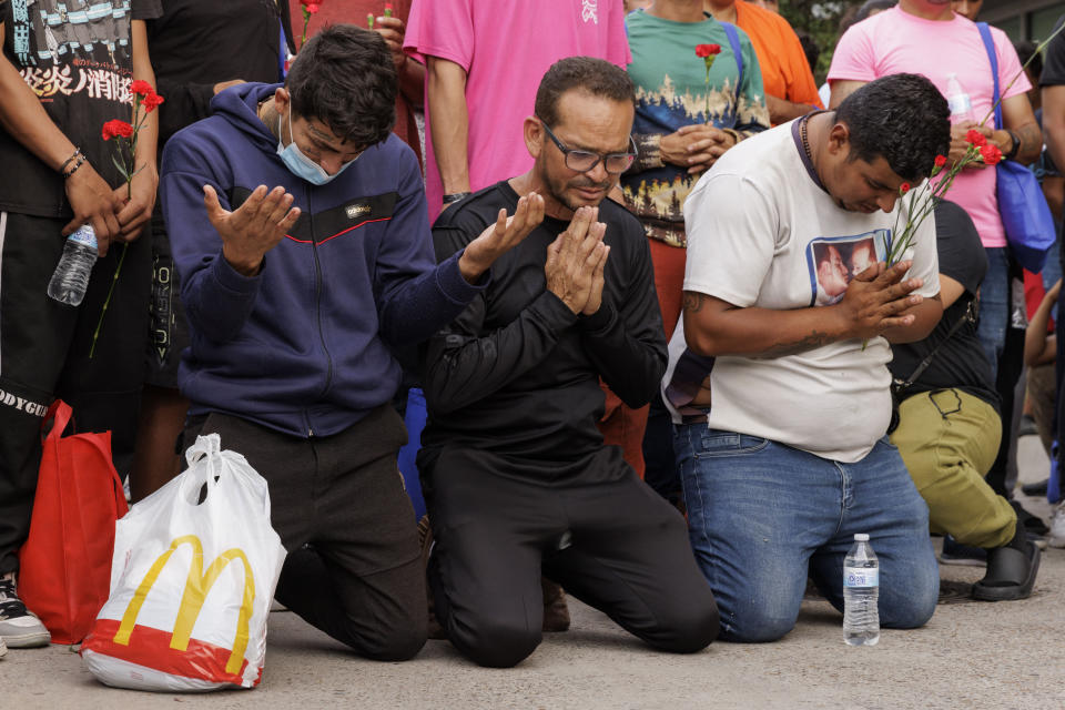 Migrants bow their heads during a prayer at a vigil for the eight migrants that were killed and several others that were injured the day before while waiting at a bus stop, in Brownsville, Texas, Monday, May 8, 2023. (AP Photo/Michael Gonzalez)