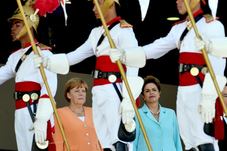 German Chancellor Angela Merkel (L) and Brazilian President Dilma Rousseff listen to their national anthems during the welcoming ceremony at Planalto Palace in Brasilia, on August 20, 2015