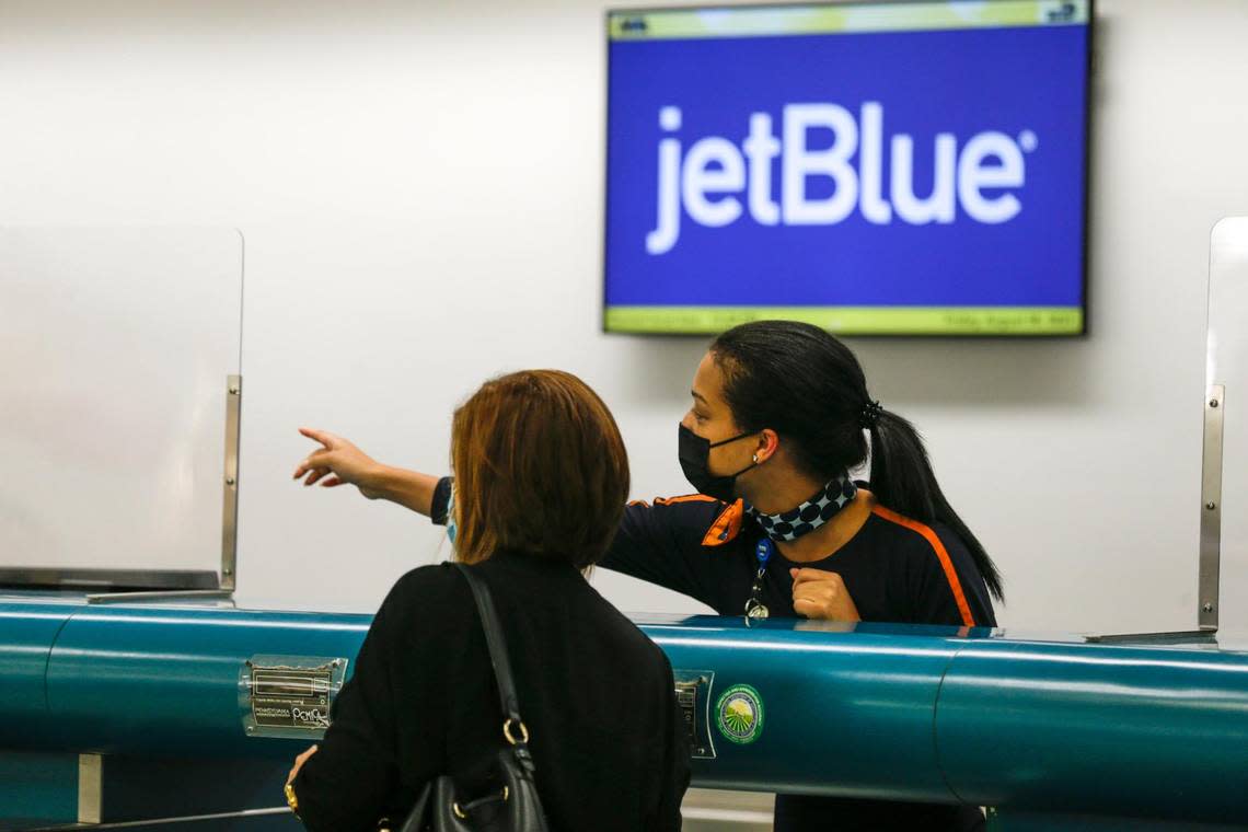 An employee at the JetBlue ticket counter shows the way to a traveler at Miami International Airport in Miami, Florida, on Aug. 6, 2021.