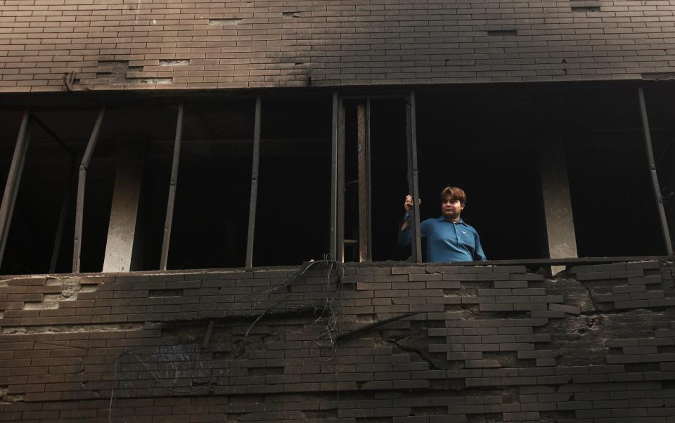 A man looks through the window of a damaged building after it was hit by a bomb blast, which happened on Sunday, in Peshawar