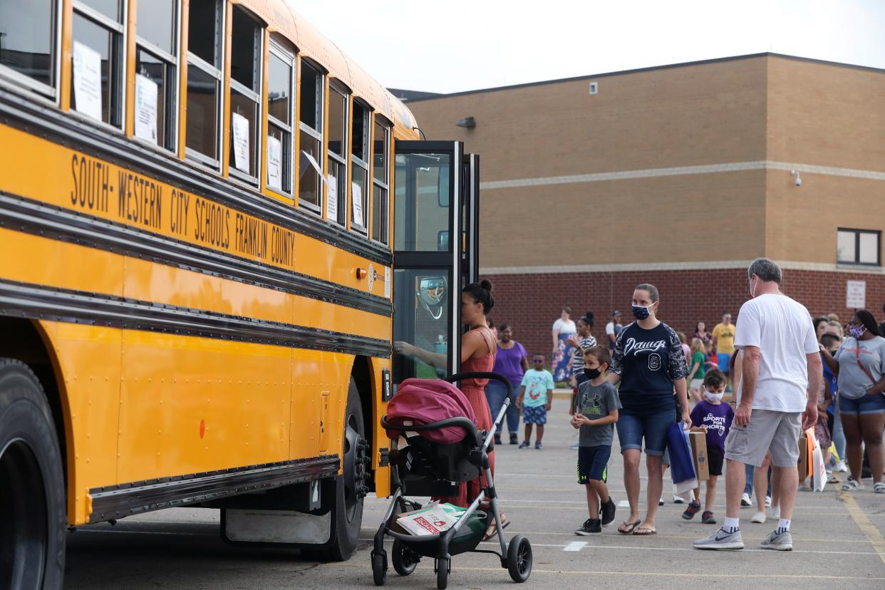 Parents and students line up to board a school bus as part of the first-time bus-rider program at the South-Western City School District's kindergarten open house Aug. 7 at Central Crossing High School in Grove City.