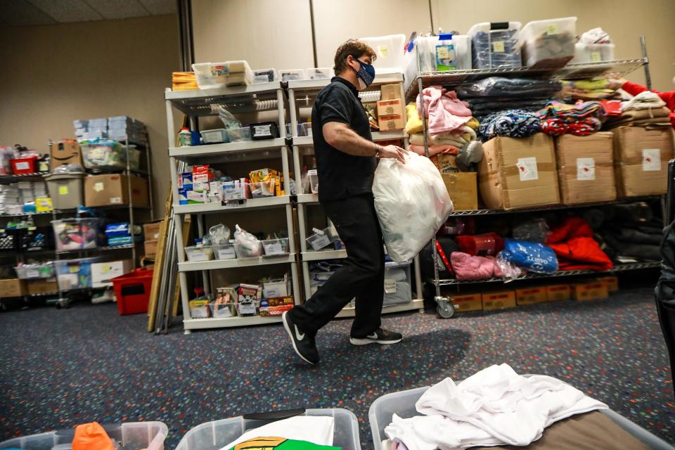 Ford Motor Co. CEO Jim Farley grabs bags to pack up vital resources to hand out to guests at the Pope Francis Center in the TCF Center in downtown Detroit on March 6, 2021.