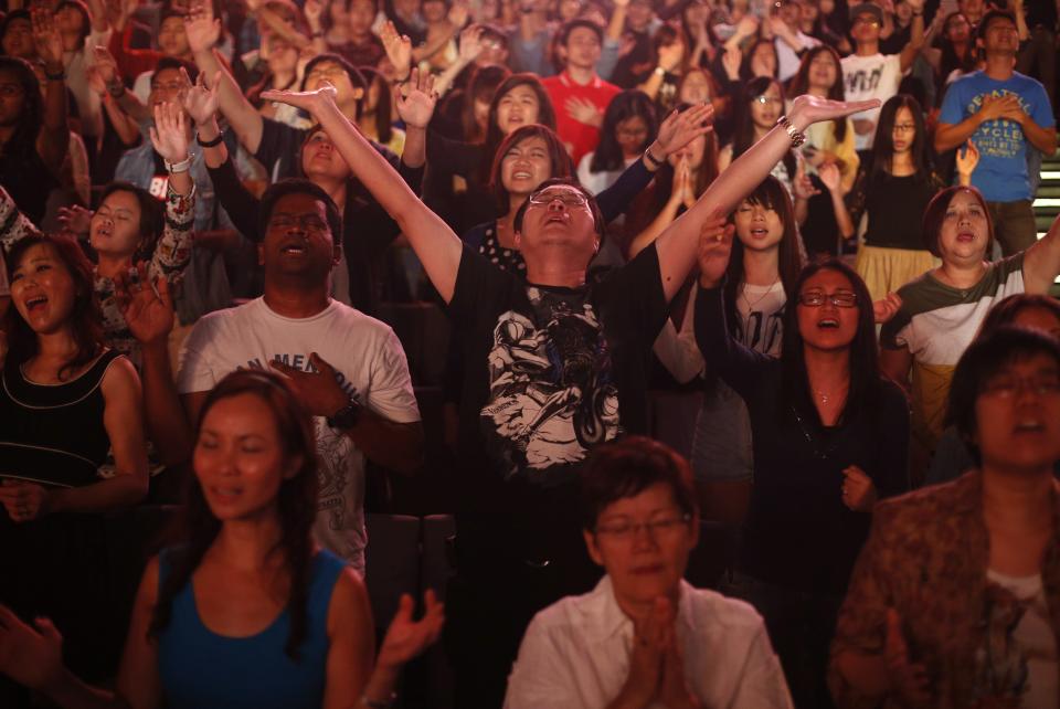 Worshippers attend a church service at the City Harvest Church in Singapore March 1, 2014. With a "prosperity gospel" that blends the spiritual and the material, City Harvest and other Pentecostal megachurches in the wealthy Asian city-state have perfected a popular and lucrative model. Now they are working to export it to the world and turn Singapore into a hub for evangelical Christianity. Picture taken March 1, 2014. To match Feature SINGAPORE-MEGACHURCHES/ REUTERS/Edgar Su (SINGAPORE - Tags: RELIGION)