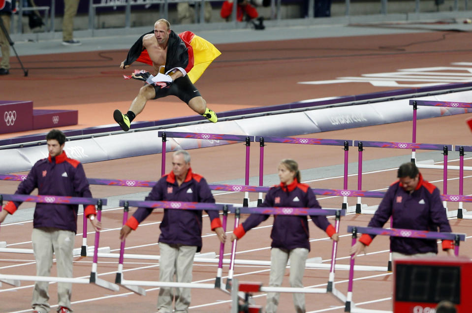 Germany's Robert Harting jumps over a hurdle as he celebrates winning the men's discus throw final during the London 2012 Olympic Games at the Olympic Stadium August 7, 2012. Harting won gold ahead of Iran's Ehsan Hadadi who took silver and Estonia's Gerd Kanter who won bronze. REUTERS/Stefan Wermuth (BRITAIN - Tags: SPORT ATHLETICS OLYMPICS) 