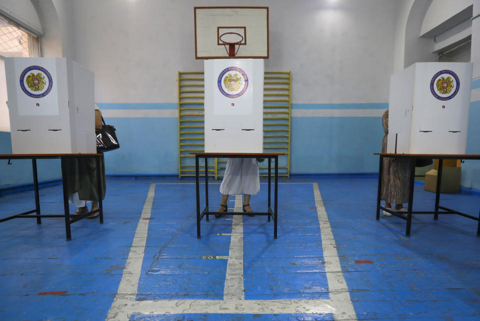 People read their ballot papers at a polling station during a parliamentary election in Yerevan, Armenia, Sunday, June 20, 2021. Armenians are voting in a national election after months of tensions over last year's defeat in fighting against Azerbaijan over the separatist region of Nagorno-Karabakh. (AP Photo/Sergei Grits)