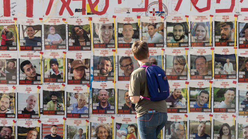 A woman looks at a wall of photos of hostages captured by Hamas on October 7, displayed in Tel Aviv. - Amir Levy/Getty Images