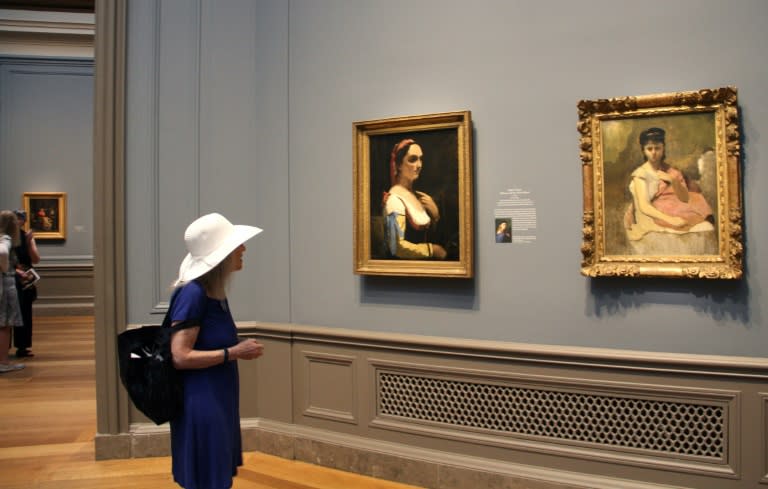 A woman looks at Jean-Baptiste-Camille Corot's "Italian Woman (Woman with the Yellow Sleeve)" (c. 1870), left, and " Woman with a Pink Shawl" (c. 1865–1870) at the National Gallery of Art in Washington