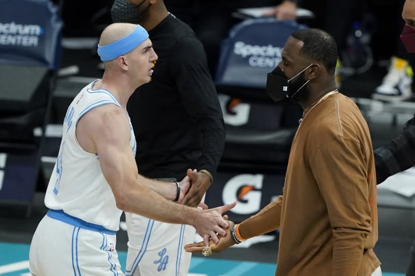 Los Angeles Lakers forward LeBron James, right, greets guard Alex Caruso during a time out during the second half in an NBA basketball game against the Charlotte Hornets on Tuesday, April 13, 2021, in Charlotte, N.C. (AP Photo/Chris Carlson)