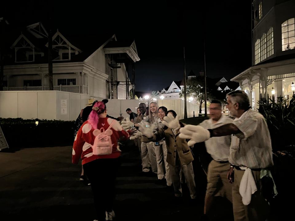 grand floridian employees lined up wearing mickey mouse hands giving guests high fives