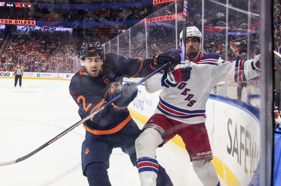 New York Rangers' Julien Gauthier (12) is checked by Edmonton Oilers' Evan Bouchard (2) during the first period of an NHL hockey game Friday, Feb. 17, 2023, in Edmonton, Alberta. (Jason Franson/The Canadian Press via AP)