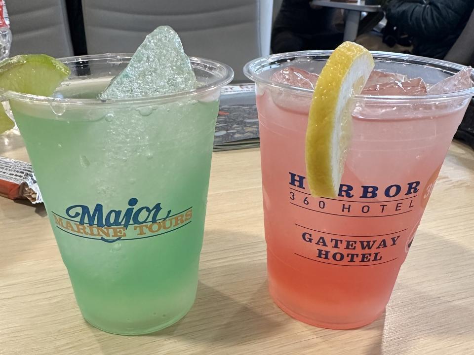 Two margaritas: a green one on the right, and a pink one on the left, with large chunks of ice inside.