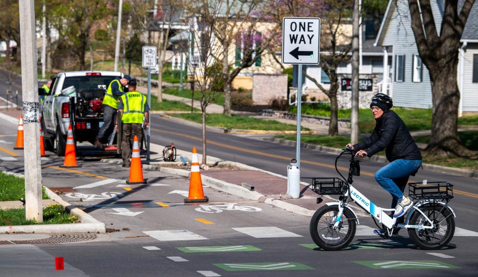 A person rides an electric bike across the intersection of Seventh and Dunn streets in April.
