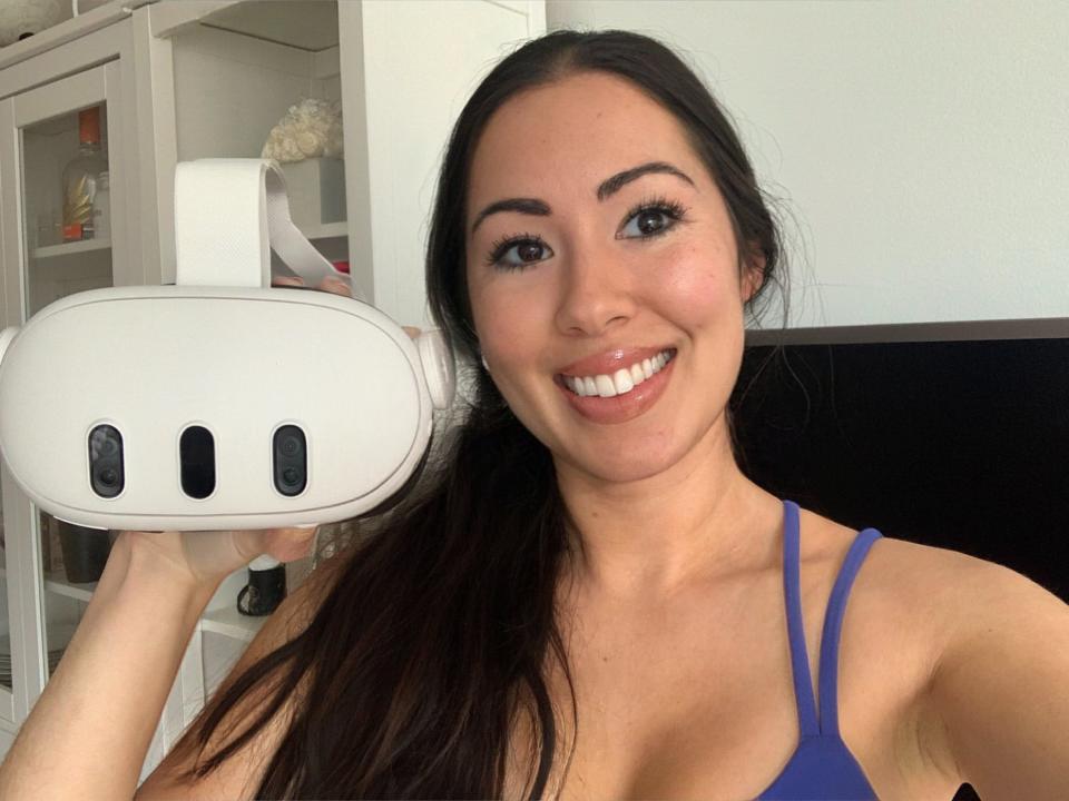 Selfie of the writer, wearing a purple workout tank top, holding a Meta VR headset