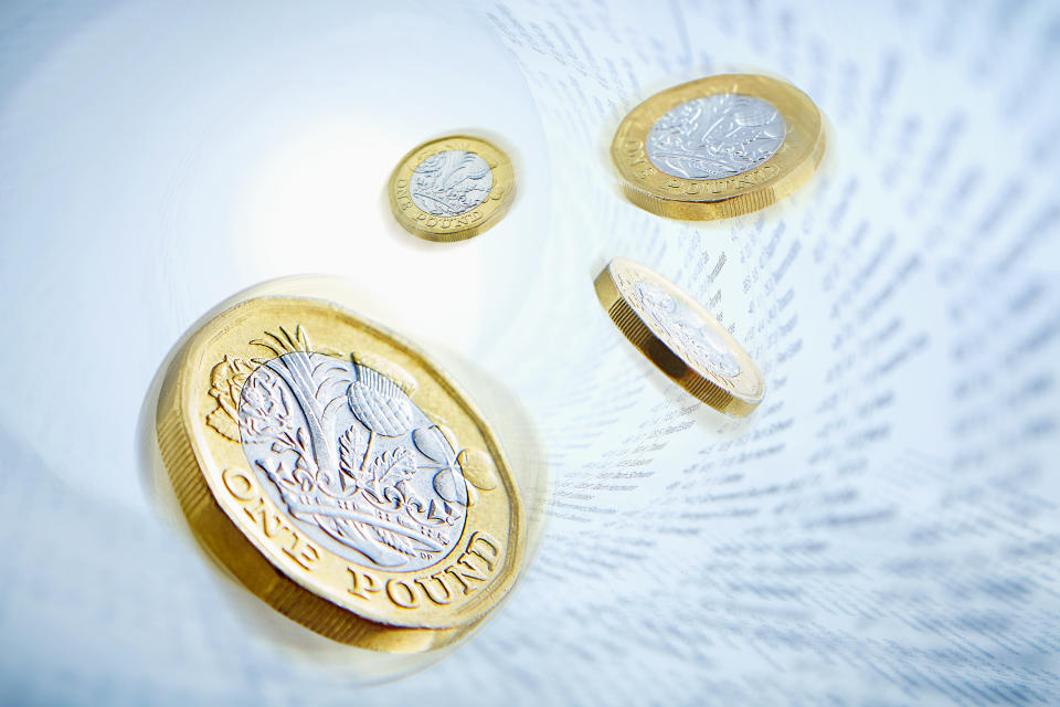 One pound coins surrounded by stock market data