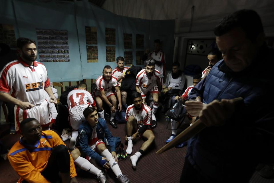 In this Sunday, Feb. 5, 2017, coach of Hope Refugee Football Club Antreas Sampanis, right, gives directions to his players before a soccer match in western Athens. On weekends they play in an amateur league against teams made up of professional groups like lawyers, telecom workers, and accountants. (AP Photo/Thanassis Stavrakis)