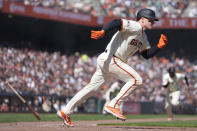 San Francisco Giants' Matt Chapman heads toward first after hitting a groundout that scored LaMonte Wade Jr., rear, during the sixth inning of the team's baseball game against the San Diego Padres in San Francisco, Friday, April 5, 2024. (AP Photo/Eric Risberg)