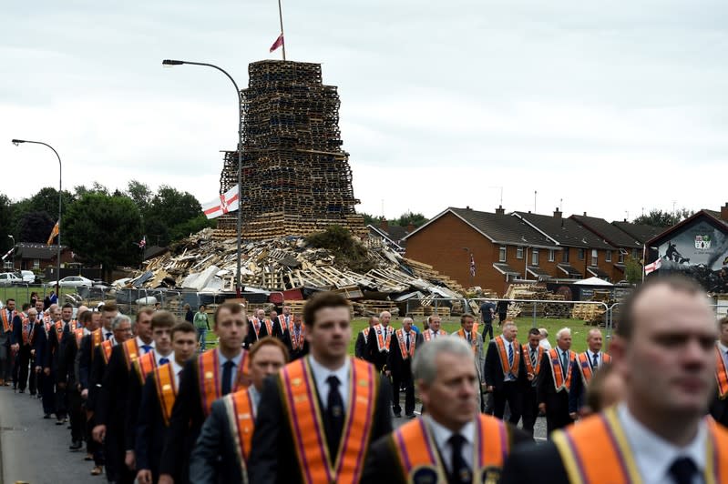 FILE PHOTO: Participants in an Orange Order parade march past a bonfire pyre in Portadown