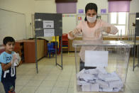 A woman casts her ballot at a polling station during Turkish Cypriots election for a new leader in the Turkish occupied area in the north part of the divided capital Nicosia, Cyprus, Sunday, Oct. 18, 2020. Turkish Cypriots vote to choose a leader who'll explore, with rival Greek Cypriots, whether there's enough common ground left for a deal to end the island's decades of ethnic division. (AP Photo/Nedim Enginsoy)