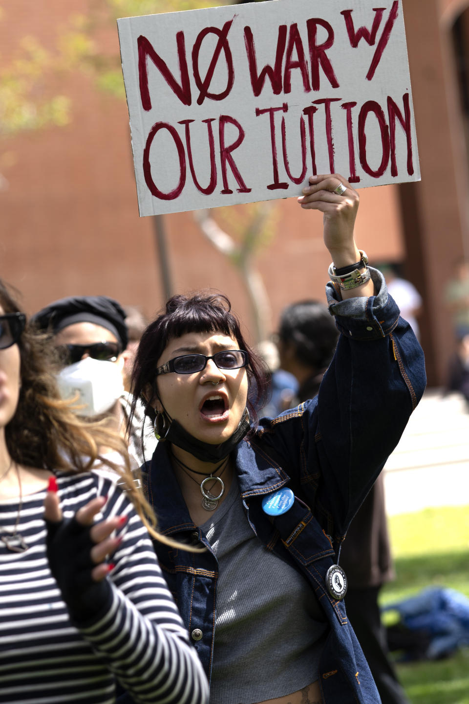 University of Southern California protester raises an anti war sign in Alumni Park on the campus of the University of Southern California during a pro-Palestinian occupation on Wednesday, April 24, 2024 in Los Angeles. (AP Photo/Richard Vogel)