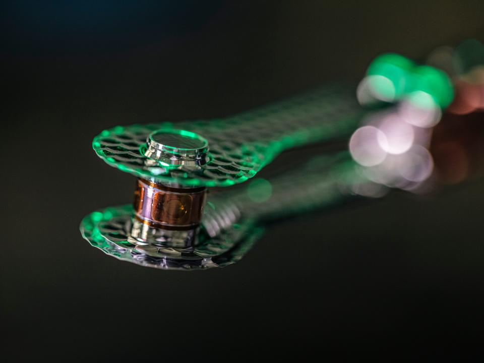 A a gold-plated hohlraum from the National Ignition Facility glows green against a black background