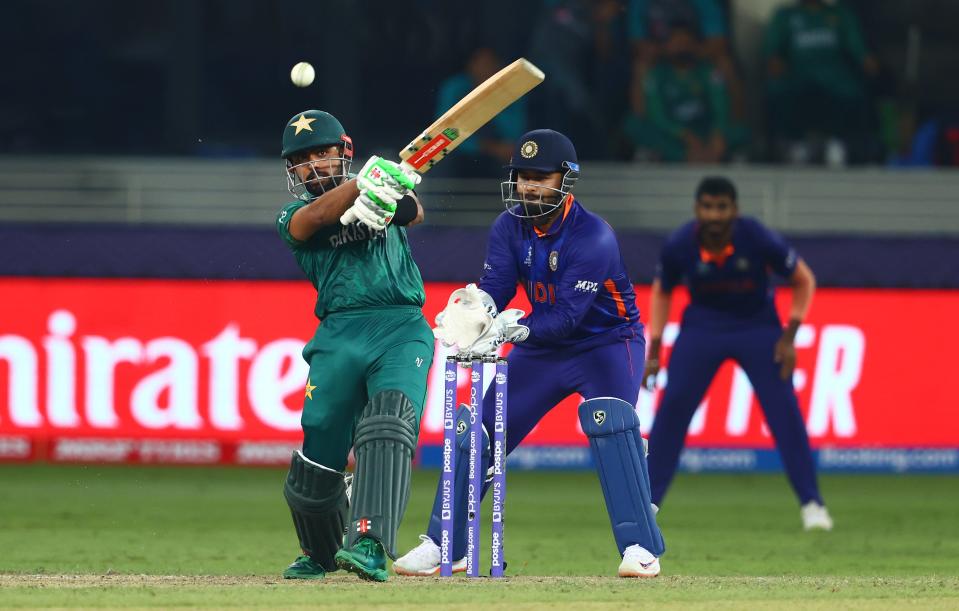 Babar Azam of Pakistan plays a shot as Rishabh Pant of India looks on during the ICC Men's T20 World Cup match between India and Pakistan at Dubai International Stadium on October 24, 2021 in Dubai, United Arab Emirates.