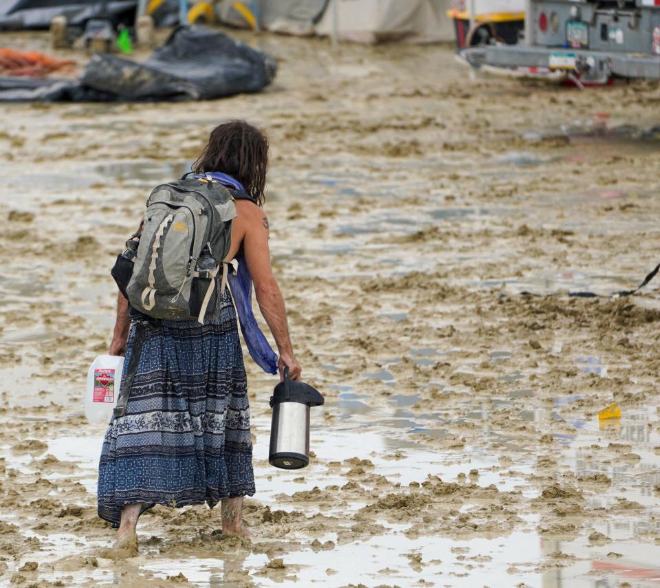 Un participante de Burning Man se abre paso entre el barro.