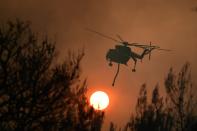 An helicopter operates during a wildfire in Kryoneri area, northern Athens, Greece, Thursday, Aug. 5, 2021. Wildfires rekindled outside Athens and forced more evacuations around southern Greece Thursday as weather conditions worsened and firefighters in a round-the-clock battle stopped the flames just outside the birthplace of the ancient Olympics. (AP Photo/Michael Varaklas)