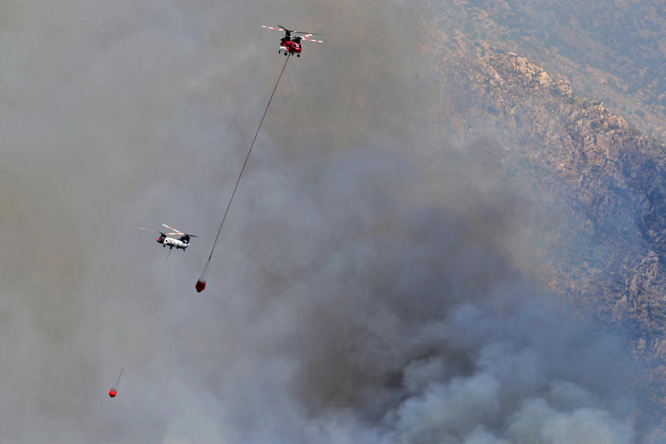 Wildfire air attack helicopters continue to battle the Bighorn Fire along the western side of the Santa Catalina Mountains, Friday, June 12, 2020, in Oro Valley, Ariz. Hundreds of homes on the outskirts of Tucson remain under an evacuation notice as firefighters work to keep the wildfire from moving downhill from canyons and ridges in the Coronado National Forest. (AP Photo/Matt York)