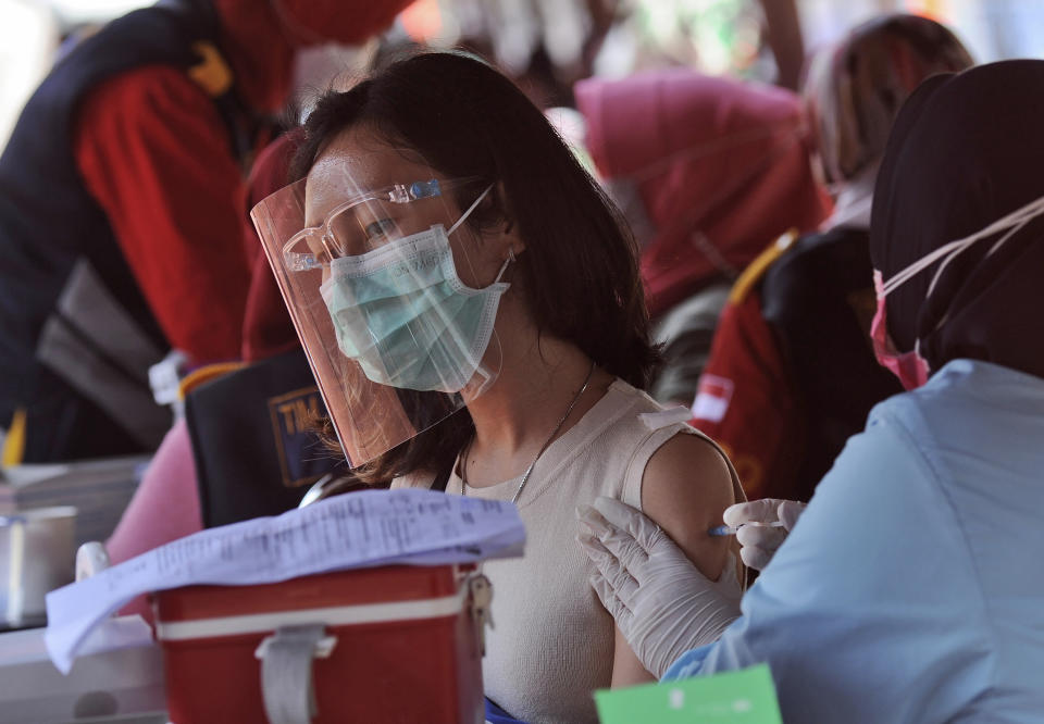 A woman receives a shot of the Sinovac COVID-19 vaccine at a soccer stadium in Bandung, West Java, Indonesia, Thursday, June 17, 2021. Indonesia's president ordered authorities to speed up the country's vaccination campaign as the World Health Organization warned Thursday of the need to increase social restrictions in the country amid a fresh surge of coronavirus infections caused by worrisome variants. (AP Photo/Bukbis Candra)