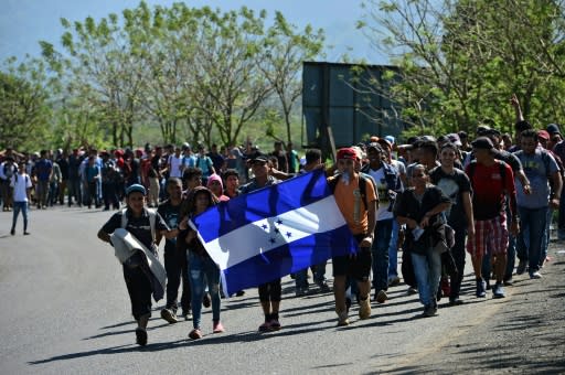 Honduran migrants walk behind a Honduran national flag heading to Puerto Barrios in Guatemala, after breaking through the country's southern border with Honduras