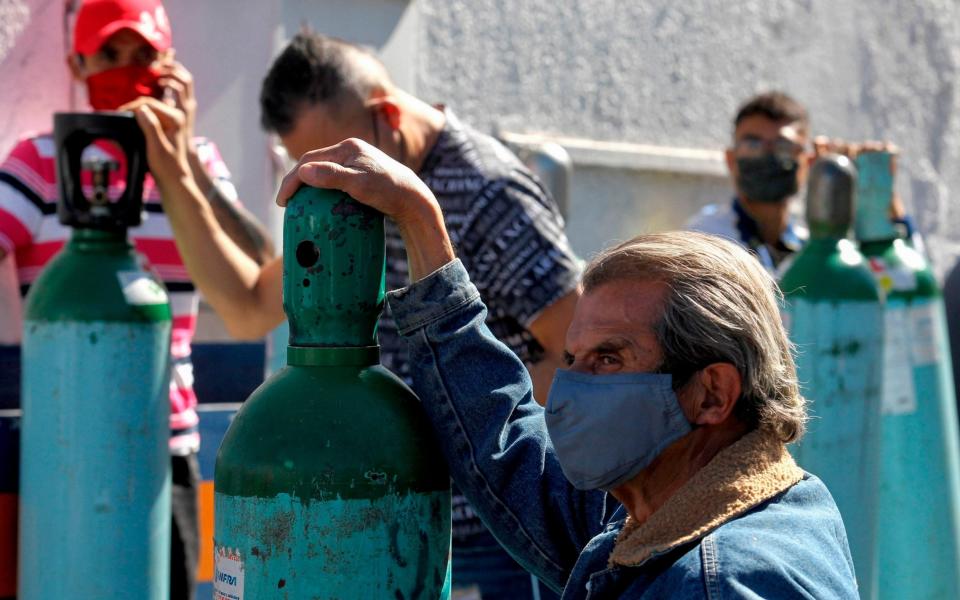 People queue to refill oxygen tanks for their relatives infected with COVID-19, due to shortage in medicinal gas following an increase in coronavirus cases, - ULISES RUIZ / AFP