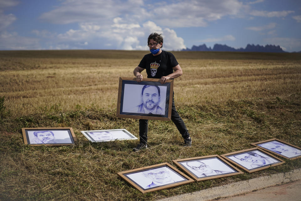 A man places drawings of Catalan separatist leaders jailed for sedition outside Lledoners prison in Sant Joan de Vilatorrada, near Barcelona, Spain, Tuesday, June 22, 2021. Nine Catalan separatist leaders jailed for sedition are eyeing freedom, after Spain's Cabinet pardoned them in the hope of starting what Prime Minister Pedro Sánchez called a much-needed reconciliation in the country's restive northeast. (AP Photo/Joan Mateu)