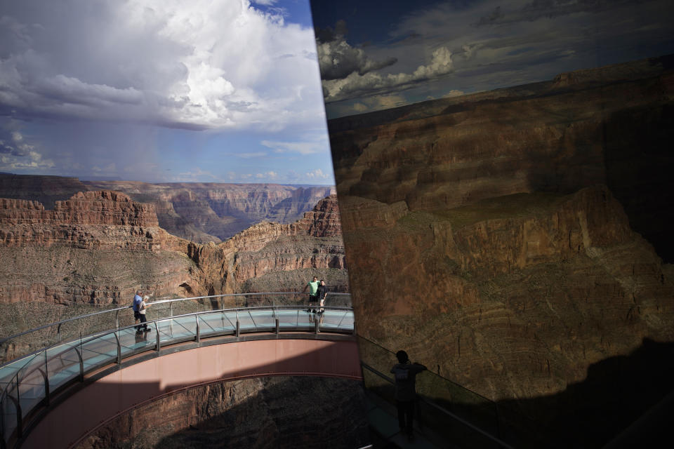 A reflection in glass shows part of the Grand Canyon as people walk across the Grand Canyon Skywalk on Hualapai reservation Tuesday, Aug. 16, 2022, in northwestern Arizona. Roughly 600,000 tourists a year visit the Grand Canyon on the Hualapai reservation in northwestern Arizona — an operation that's the tribe's main source of revenue. (AP Photo/John Locher)