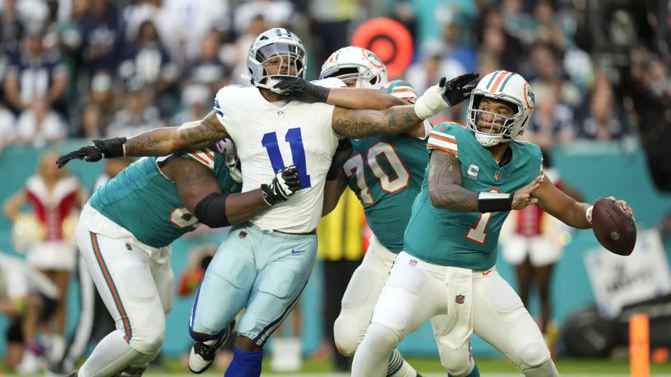 Miami Dolphins quarterback Tua Tagovailoa stands back to pass as Dallas Cowboys linebacker Micah Parsons is held back by Miami's offensive line on Christmas Eve 2023. - Rebecca Blackwell/AP