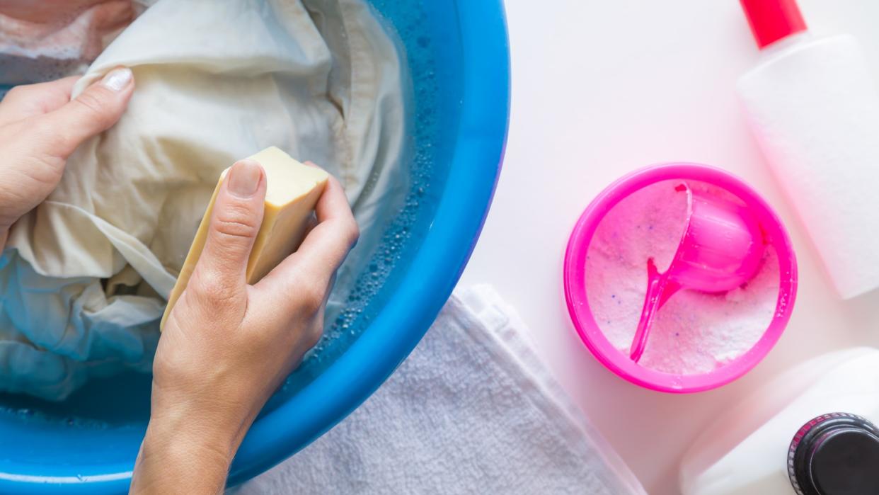 Housewife washing clothes with different detergents in the bowl.