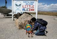 An attendee poses an alien doll at the Little A'Le'Inn as an influx of tourists responding to a call to 'storm' Area 51, a secretive U.S. military base believed by UFO enthusiasts to hold government secrets about extra-terrestrials, is expected