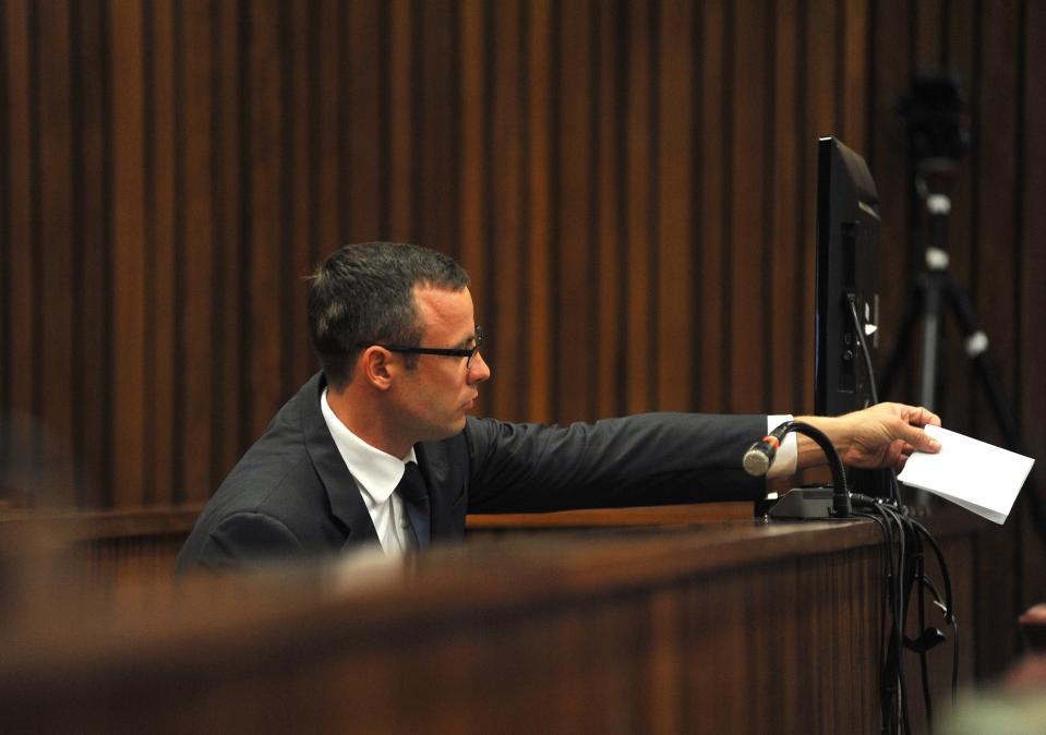 Oscar Pistorius passes a note to his defense team in high court in Pretoria, South Africa, Monday, March 24, 2014. The trial of Pistorius, who is charged with murder for the shooting death of his girlfriend Reeva Steenkamp on Valentines Day in 2013, is beginning its fourth week. (AP Photo/Ihsaan Haffejee, Pool)