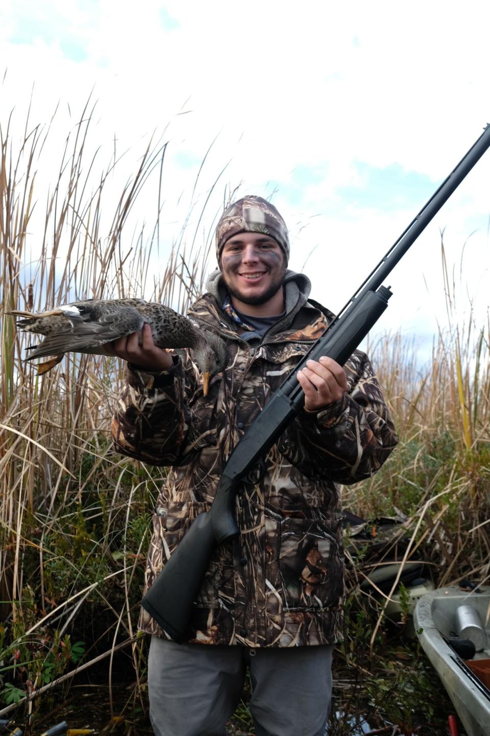 duck hunter holding gadwall duck and gun