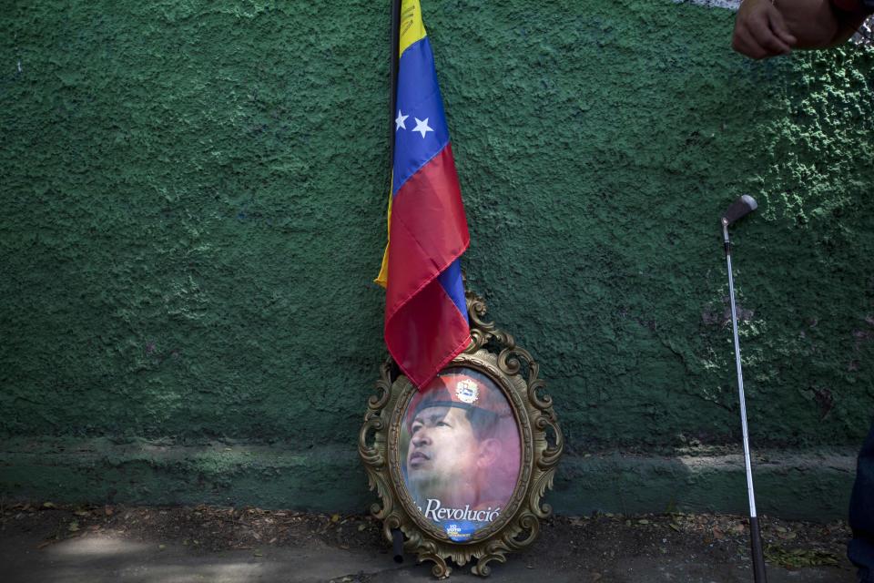 FILE - In this Oct. 3, 2012 file photo, a framed image of Venezuela's President Hugo Chavez is propped up against a wall, under a Venezuelan flag next to a golf club at a campaign rally in Maracay, Venezuela. After four election wins, Chavez is on track to completing at least 20 years in power. (AP Photo/Rodrigo Abd, File)