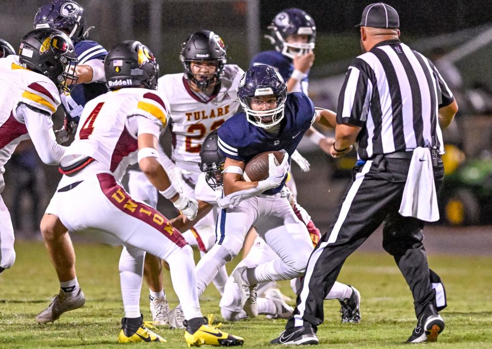 Redwood's Jimmie Burk tries to evade Tulare Union defenders in non-league high school football on Friday, September 6, 2024.